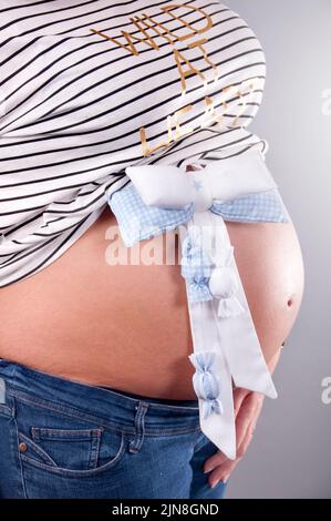 Eine Schwangere mit einer Baby-Schleife auf ihrem Bauch Stockfoto