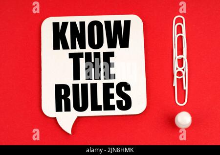Geschäftskonzept. Auf einem roten Hintergrund sind Büroklammern ein Ausrufezeichen und ein Gedankenschild mit der Aufschrift - kennen Sie die Regeln Stockfoto