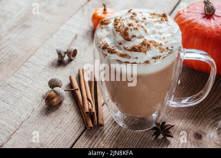 Herbstlich würziges Heißgetränk mit Schlagsahne und Zimt auf Holzboden Stockfoto