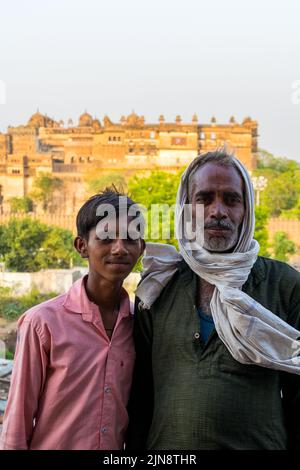 Eine vertikale Aufnahme des indischen Mannes und seines Sohnes mit dem Orchha Fort Complex im Hintergrund Stockfoto