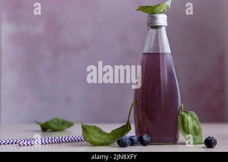 Erfrischende Bio-Cocktail-Flasche mit Blaubeeren, Samen, Basilikumextrakt, Blättern. Sommer gesundes asiatisches Getränk. Verschwommener Vordergrund. Stockfoto