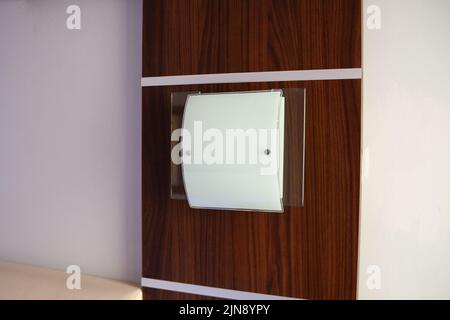 Wandleuchte an leerer Wand. Wandpaneele aus Holz. Moderne quadratische Lampe Stockfoto