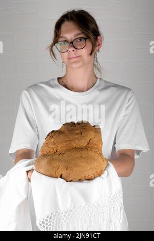 Junge Frau mit dem Brot von Mdera, Pane di Miera auf weißem Hintergrund, typisch süditalienisches Sauerteigbrot Stockfoto