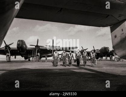 Eine Besatzung der RAF-Staffel Nr. 502 geht zu ihrem Flugzeug vorbei an anderen Handley Page Halifax Mark IIIs in Stornoway, Äußere Hebriden. Der Halifax war ein viermotoriger schwerer Bomber der britischen Royal Air Force (RAF), der mit dem Rolls-Royce Merlin-Motor angetrieben wurde. Sowohl die Halifax als auch Lancaster entwickelten sich zu leistungsfähigen viermotorigen strategischen Bombern, von denen Tausende während des Krieges von der RAF und mehreren anderen Diensten gebaut und betrieben wurden. Stockfoto