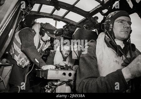 An Bord eines Whitley VII der Squadron Nr. 502 während einer Anti-U-Boot-Patrouille im Jahr 1942. Im engen Cockpit konsultiert der Skipper mit seinem Navigator, während der zweite Pilot das Flugzeug fliegt. Die Armstrong Whitworth A.W.38 Whitley war ein britisches Medium-Bomber-Flugzeug der 1930, das auch von Coastal Command eingesetzt wurde. Der erste U-Boot-Tod, der der Whitley Mk VII zugeschrieben wird, war der Untergang des deutschen U-Bootes U-751 am 17. Juli 1942, der in Kombination mit einem Lancaster-Schwerbomber erreicht wurde. Stockfoto