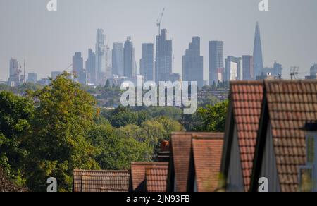 Wimbledon, London, Großbritannien. 10. August 2022. Wolkenkratzer im Zentrum Londons schimmern im Hitzerusch über den Häusern auf dem Wimbledon Hill, während die Temperaturen im Südosten Englands weiter steigen. Quelle: Malcolm Park/Alamy Live News. Stockfoto