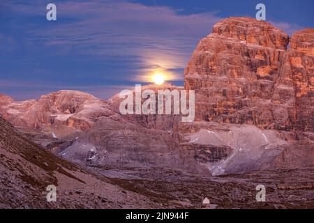 Mondaufgang auf einem Berg mit einer Kapelle im Tal Stockfoto