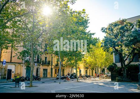 Blick auf die Straße von Barcelona Poble Nou Nachbarschaft an einem Sommertag mit Menschen Fahrrad fahren. Straßenszene der spanischen Stadt im Sommer Stockfoto