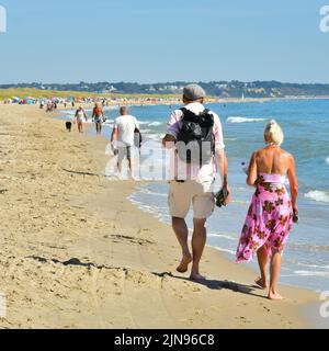 Studland Beach, Shell Bay, Dorset, Großbritannien, 10.. August 2022, Wetter. Heiß und sonnig zu Beginn einer weiteren Hitzewelle. Eine Gruppe von Kajakfahrern geht in der hellen Morgensonne aufs Meer. Menschen, die bei strahlendem Sonnenschein am Ufer entlang gehen. Kredit: Paul Biggins/Alamy Live Nachrichten Stockfoto