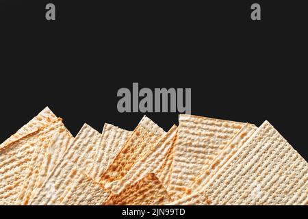 Ein Foto von Matza oder Matza-Stücken auf schwarzem Hintergrund. Matza für die jüdischen Passahfeiertage. Platz für Text, Platz zum Kopieren Stockfoto