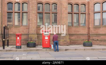 Barrow in Furness vereinigtes Königreich Juni 18 2022 älterer Mann, der auch daneben stand, zwei rote königliche Briefkästen Stockfoto
