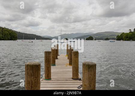 Betws- y- coed Wales vereinigtes Königreich Mai 21 2022 hölzerner Steg, der zu einem stürmisch aussehenden Bootssee führt, viele Boote auf dem Wasser Stockfoto