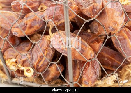 Mehrere Zweige mit trockenen süßen Datteln in einem Korb, Nahaufnahme. Stockfoto