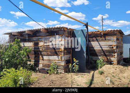 Garagenschuppen aus Eisenbahnsabeln. Kleines Nebengebäude in der Nähe des privaten Hauses. Stockfoto