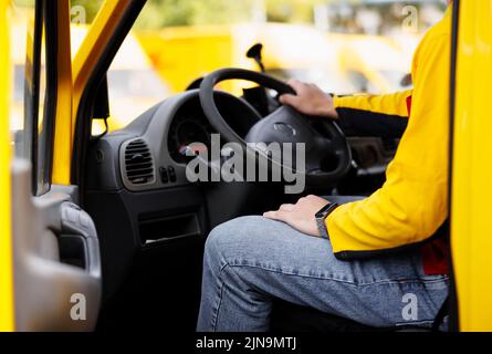 Ein uniformierte Mitarbeiter. Der Lieferer liest für das Fahren des Transporters Stockfoto