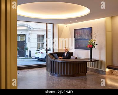 Rezeptionstresen und Blick auf die Straße. 30 St James' Square, London, Großbritannien. Architekt: Eric Parry Architects Ltd, 2021. Stockfoto