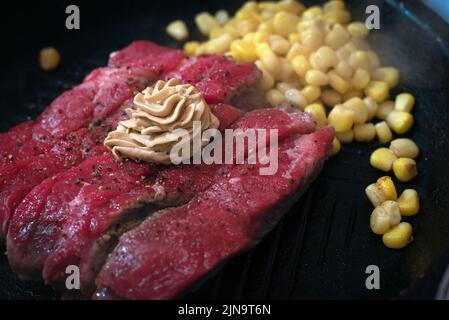 Seltenes Rindersteak auf einem heißen Teller mit Maiskörnern Stockfoto