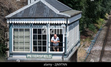 Der Signalmann schaut aus der Signalbox an der Petersfield Station, Hampshire. Stockfoto