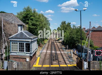 Signalbox an der Petersfield Station entlang der Bahngleise und Bahnübergang. Stockfoto