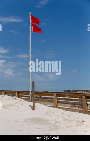 Doppelte rote Fahnen vor blauem Himmel zeigen an, dass der Strand wegen gefährlicher Bedingungen zum Schwimmen gesperrt ist. Stockfoto