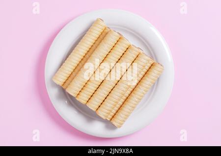 Cremige Waffel rollt in Teller auf einem rosa Hintergrund, Draufsicht Stockfoto