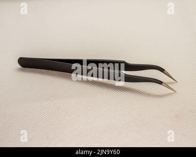 Professionelle schwarze Pinzette, horizontal isoliert auf weißem Studiopapier dargestellt, mit weichem Fokus fotografiert Stockfoto