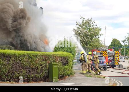 Essex Fire and Rescue Service Feuerwehrmann & Feuerwehrgruppe Feuerwehrmänner Feuerwehrmänner sprühen Wasserstrahl auf den Hausbrand Rauch und Flammen England Großbritannien Stockfoto