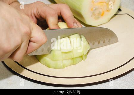 Rezept für Zucchini-Krapfen. Schritt 2 - Zucchini schneiden. Hände schneiden grüne Zucchini in Würfel. Kochen veganer Gemüsepfannkuchen. Stockfoto