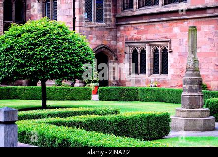 Die Baronial Hall der Chethams Music School, Manchester, Großbritannien, wurde im 15. Jahrhundert erbaut, mit dem Hyde Cross im Vordergrund. Im Gebäude befindet sich derzeit die Bibliothek. Das Kreuz erschien auf einer Karte von Manchester aus dem Jahr 1650 als lateinisches Kreuz auf einem Sockel und stand bis in die 1840er Jahre an einer nahe gelegenen Straßenkreuzung. Chetham's unterrichtet Schüler und Studenten zwischen 8 und 18 Jahren. Chetham's Library ist die älteste kostenlose öffentliche Bibliothek im englischsprachigen Raum. Stockfoto