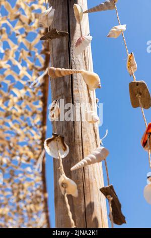 Muscheln hängen an der Holzpfosten am Strand. Sommerkonzept. Reisen und Tourismus Stockfoto