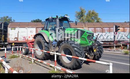 Viersen, Deutschland. 10. August 2022. Nach einer Kollision an einem Bahnübergang steht ein Traktor vor einem Güterzug. Auf einem Bahnübergang in Viersen hielt am Mittwoch aus ungeklärten Gründen ein Traktor auf den Gleisen. Ein herannahender Güterzug konnte nicht bremsen und stürzte in einen der Anhänger am halb verbarrten Übergang. Der Traktor hatte bereits die Gleise überquert. Der 19-jährige Traktorfahrer und der Lokführer waren unverletzt. (To dpa: 'Güterzug fährt durch Traktor-Anhänger-Kombination - keine Verletzungen') Quelle: Alexander Frostreuter/dpa/Alamy Live News Stockfoto