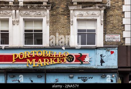 London, Großbritannien - 11. März 2022: Portobello Road Market und Straßenschild an einem alten Gebäude mit Banksy-Graffiti-Elementen. Stockfoto