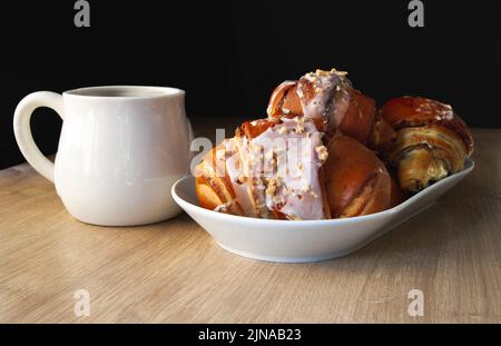 Frisches, traditionelles poliernisches Gebäck mit Mohnfüllung und Nüssen. St. Martins Croissant, Rogal Marciński oder Świętomarciński auf einem weißen Teller. Stockfoto