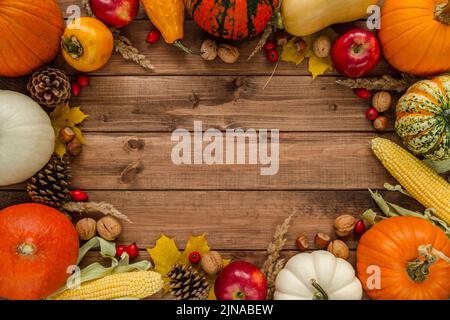 Verschiedene Kürbisse, Kürbisse, Kürbis. Flacher Rahmen mit Walnüssen, Haselnüssen, Äpfeln, Zapfen, Hagebutten, Kaki, Mais. Platz auf Holzbg kopieren. Stockfoto