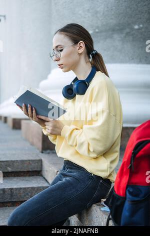Positive tägliche Affirmationen für die Selbstliebe. Junge Frau mit Kopfhörern, die in einem Notebook schreibt Stockfoto
