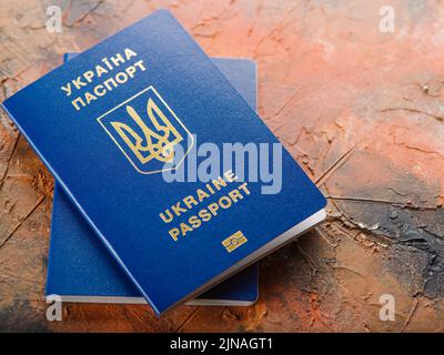 Auf einem rosafarbenen Marmorhintergrund sind zwei ukrainische biometrische Pässe zu sehen. Nahaufnahme. Internationale Reisen, persönliche Identifikation, Tourismus, Emigration. Stockfoto