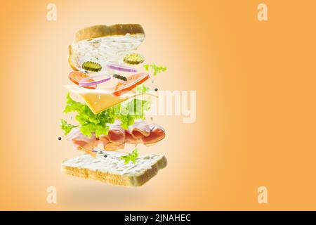 Appetitliche Burger aus Bio-Produkten - Fleisch, Gemüse, Kräuter und Käse in einem gefrorenen Flug auf orangefarbenem Hintergrund. Gesunde Lebensweise, gesunde PR Stockfoto