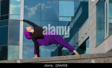 Starke Frau in Hijab Flexible Mädchen tun Yoga-Übungen auf Straße Stadt Gebäude Hintergrund Sport Dame steht in der Seitenwand auf einer Hand dehnt Körper Stockfoto