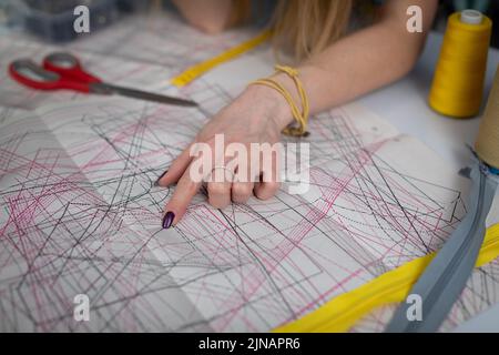 Ein Bekleidungsdesigner weist auf die Details in einem gestanzten Blatt hin. Stockfoto