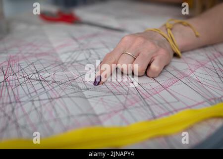Ein Bekleidungsdesigner weist auf die Details in einem gestanzten Blatt hin. Stockfoto