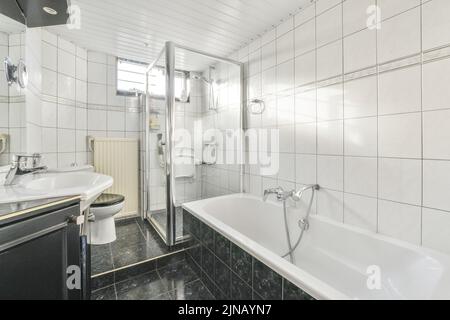 Schwarze Wand hing Toilette in minimalistischen Innenraum des Badezimmers mit Blumen auf dem Regal darüber Stockfoto