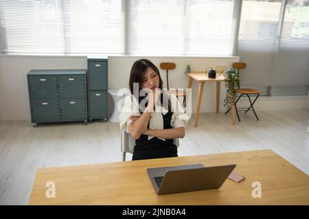 Eine beunruhigte Japanerin durch Fernarbeit im kleinen Büro Stockfoto