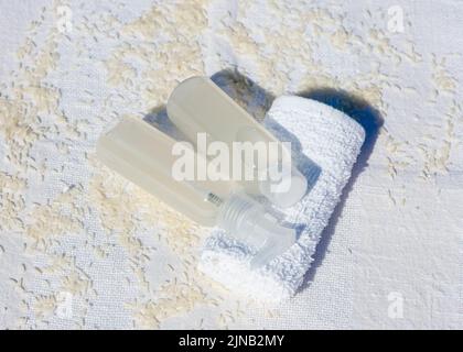 Flaschen hausgemachtes Reiswasser liegen auf weißem Handtuch, diy Hautpflegeprodukt. Stockfoto