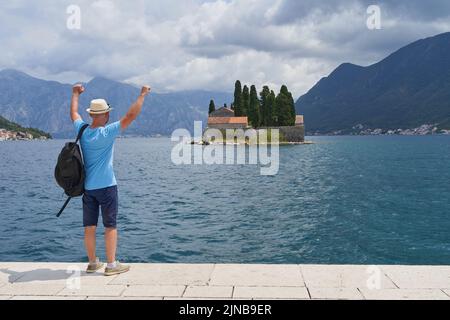 Männlicher Tourist blickt mit den Händen nach oben auf die Insel Stockfoto