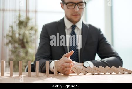 Geschäftsmann mit Dominos im Büro. Konzept Geschäftsrisiko Stockfoto