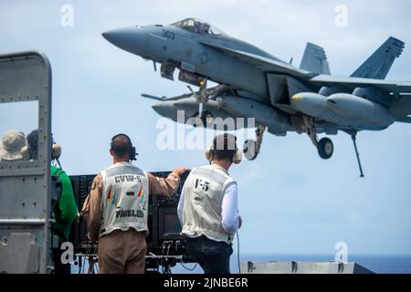 Pazifik, Usa. 09. August 2022. Seeleute der US-Marine beobachten, wie am 9. August 2022 ein F/A-18E Super Hornet Kampfflugzeug, das an der Eagles of Strike Fighter Squadron 115 befestigt ist, auf dem Flugdeck des Nimitz-Klasse Flugzeugträgers USS Ronald Reagan in der philippinischen See landet. Kredit: MC3 Gray Gibson/Planetpix/Alamy Live Nachrichten Gutschrift: Planetpix/Alamy Live Nachrichten Stockfoto