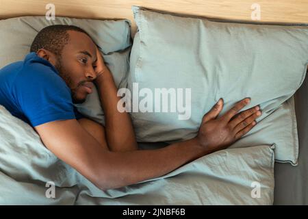 Afrikanischer Mann, Der Das Kopfende Berührt Und Nach Dem Zerfall In Der Halle An Einsamkeit Leidet Stockfoto