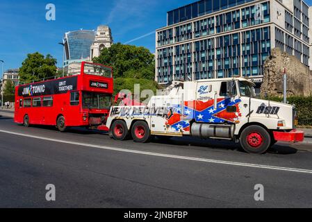 Schwere Bergung Pannenfahrzeug schleppt einen defekten Bus. Jim und Tonic Gin mobile Bar-Bus wird hinter großen amerikanischen Wrackwagen geschleppt Stockfoto