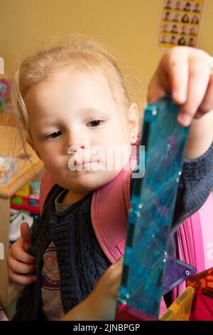 Bildung Vorschule Kinderbetreuung 2-3-jährige Kleinkind Mädchen machen Turm aus Magnet-Fliesen Stockfoto