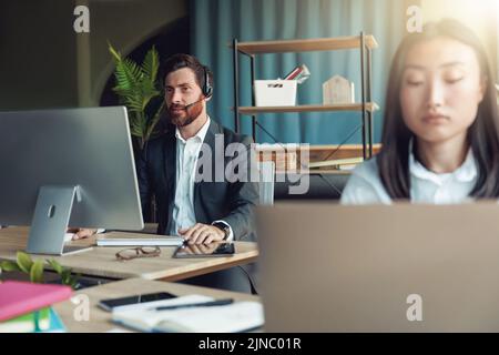 Asiatische Geschäftsfrau, die im Büro auf dem Hintergrund einer Kollegin arbeitet Stockfoto